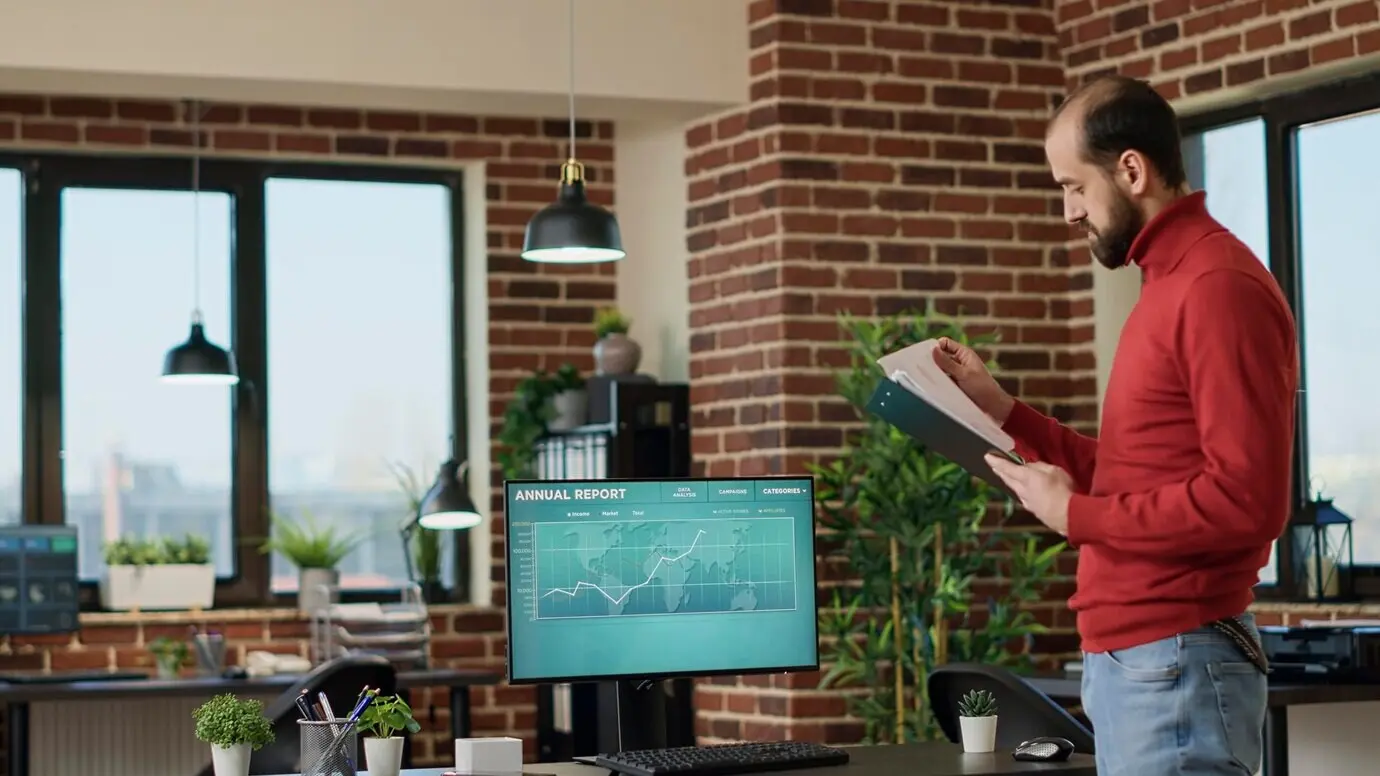 Junger Geschäftsmann nutzt auf dem Bildschirm angezeigte Gewinndaten des Handelsmarkts, um eine Finanzinvestition zu tätigen, und betrachtet Statistiken zu Aktiencharts. Ein männlicher Broker analysiert den Trend bei Hedgefonds und den Devisenmarkt.